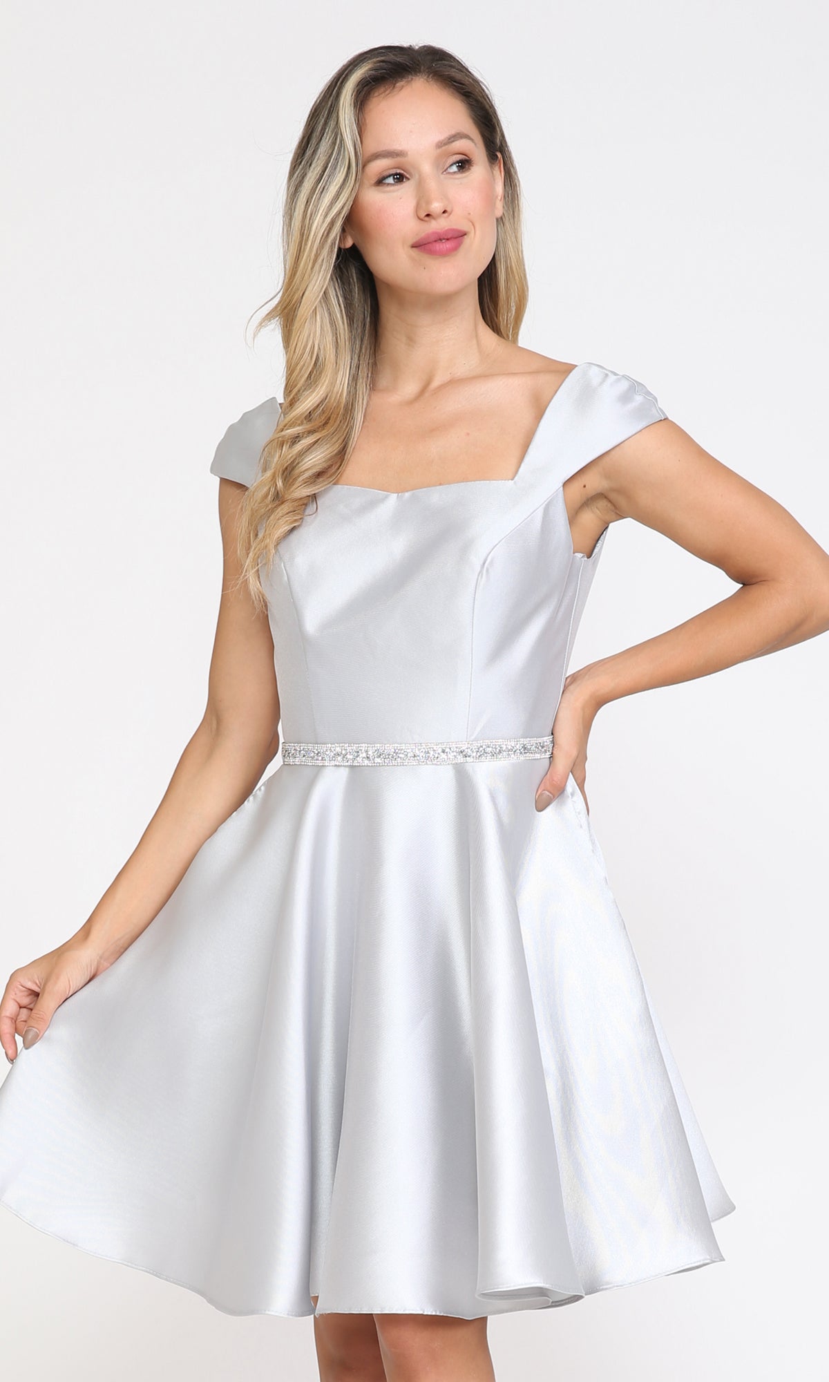 Woman in a silver Cap-Sleeve Short Homecoming Dress with Pockets 8416, featuring a flared skirt and jeweled belt—an affordable party dress—stands against a plain light background.